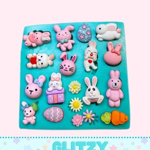 May include: A turquoise silicone mold with 16 different Easter-themed designs. The designs include bunnies, eggs, flowers, and a carrot. The mold is labeled "Glitzy Molds".