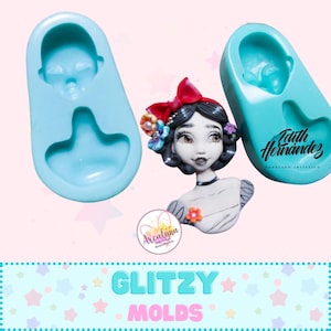 May include: A light blue silicone mold with a face design, next to a finished doll with a red bow, floral accents, and a white dress. The image also includes the text "Glitzy Molds" and the signature "Edith Hernandez".