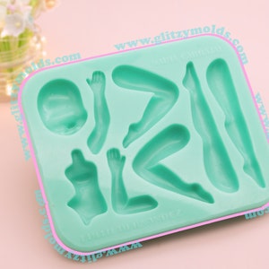 May include: A green silicone mold with seven cavities shaped like different parts of the human body, including a head, arms, and legs. The mold is labeled "Glitzy Molds" and "www.glitzymolds.com".