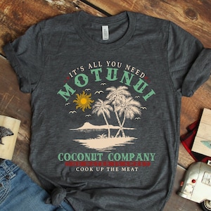 Pode incluir: Uma camiseta cinza escura com um design gr&aacute;fico que apresenta uma cena de ilha tropical com palmeiras, um sol e o texto "It's all you need Motunui Coconut Company Cook up the meat".
