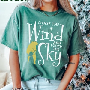 May include: A teal green t-shirt with the text "Chase the Wind and Touch the Sky" in white lettering. A yellow silhouette of a person is behind the text.