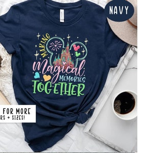May include: Navy blue t-shirt with a graphic of Cinderella's castle and Mickey Mouse ears. The text "Making Magical Memories Together" is printed on the shirt.
