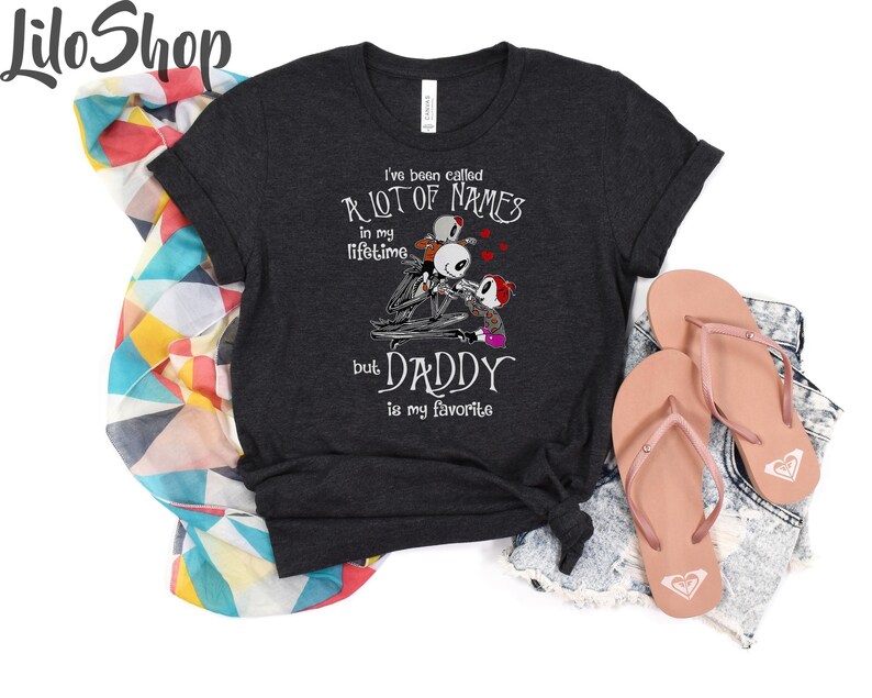 May include: A dark gray t-shirt with a white graphic print of a skeleton couple with the text "I've been called a lot of names in my lifetime but Daddy is my favorite".