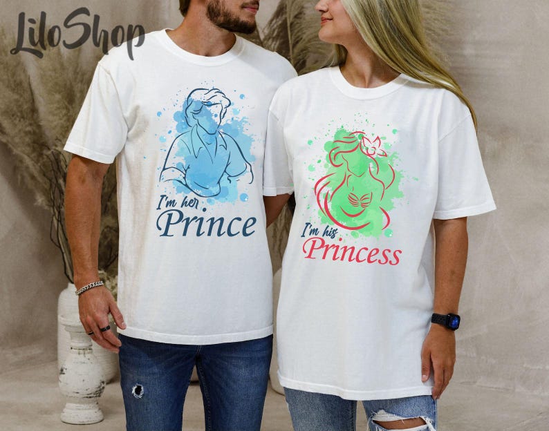 Puede incluir: Dos camisetas blancas con dise&ntilde;os a juego. Una camiseta presenta una ilustraci&oacute;n en acuarela azul de un pr&iacute;ncipe con el texto "I'm her. Prince". La otra camiseta tiene una ilustraci&oacute;n verde y roja de una princesa con el texto "I'm his. Princess."