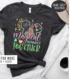 May include: Dark grey heather t-shirt with a colorful graphic of a Mickey Mouse ear silhouette with a castle and fireworks inside. The text "Making Magical Memories Together" is printed below the graphic.