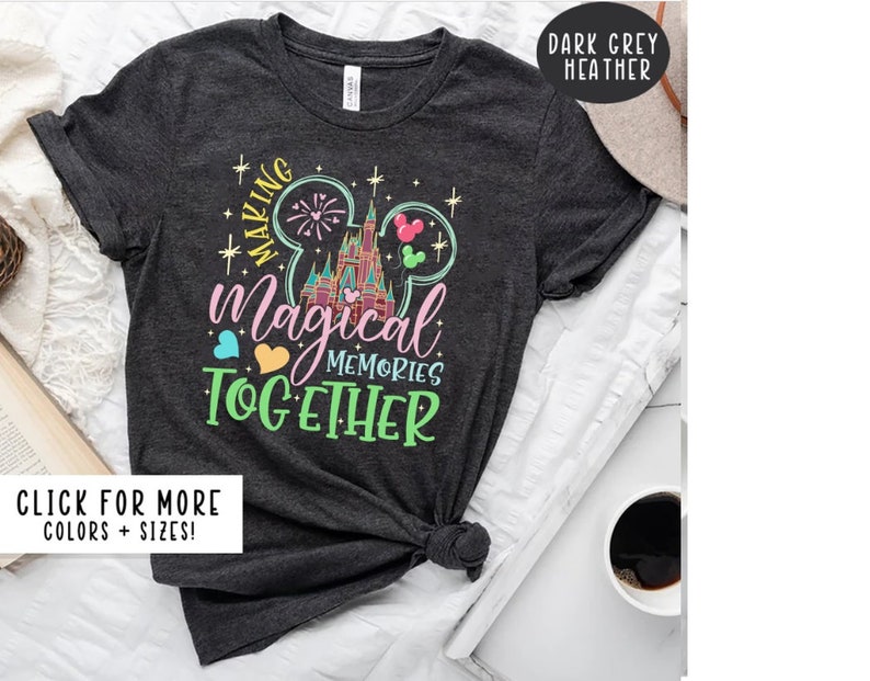 May include: Dark grey heather t-shirt with a colorful graphic of a Mickey Mouse ear silhouette with a castle and fireworks inside. The text "Making Magical Memories Together" is printed below the graphic.