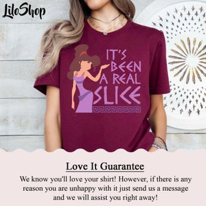 May include: Burgundy t-shirt with a purple cartoon character and the text "It's Been A Real Slice" in white. The character is wearing a purple dress and has brown hair. The text is surrounded by a Greek key pattern.