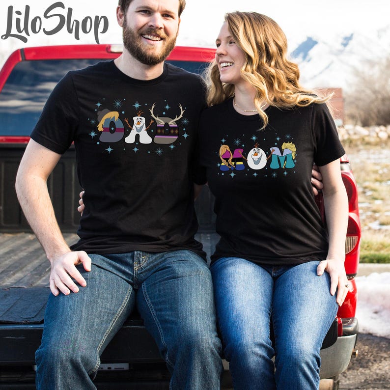 May include: Two people wearing black t-shirts with a Frozen theme. The man's shirt says 'DAD' with Olaf and Sven. The woman's shirt says 'MOM' with Elsa, Anna, and Olaf.