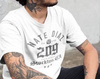 Może przedstawiać: Biała koszulka z czarnym nadrukiem graficznym, na którym widnieje napis "Nate Dial 209 Stockton, CA". Grafika zawiera również logo z tekstem "Jiu Jitsu".