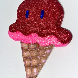 May include: A red and pink glitter ice cream cone with blue glitter eyes.