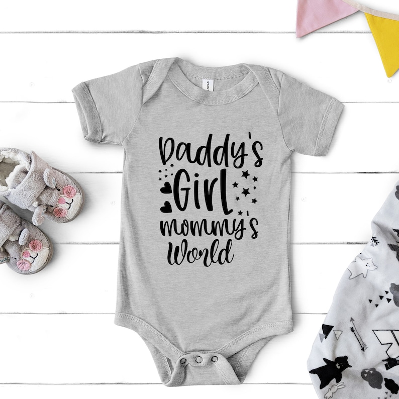 Puede incluir: Mono de beb&eacute; gris con texto negro que dice "Daddy's Girl mommy's world" con corazones y estrellas negras.