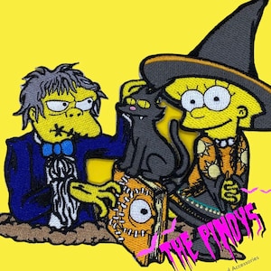 May include: An embroidered patch featuring a zombie-like character in a blue suit, a witch with a black cat and a book, and the text "The Pindys".