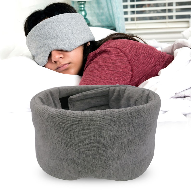 May include: Gray sleep mask with a contoured design for comfortable sleep. The mask is made of soft, breathable fabric and has a contoured shape that fits snugly around the eyes.