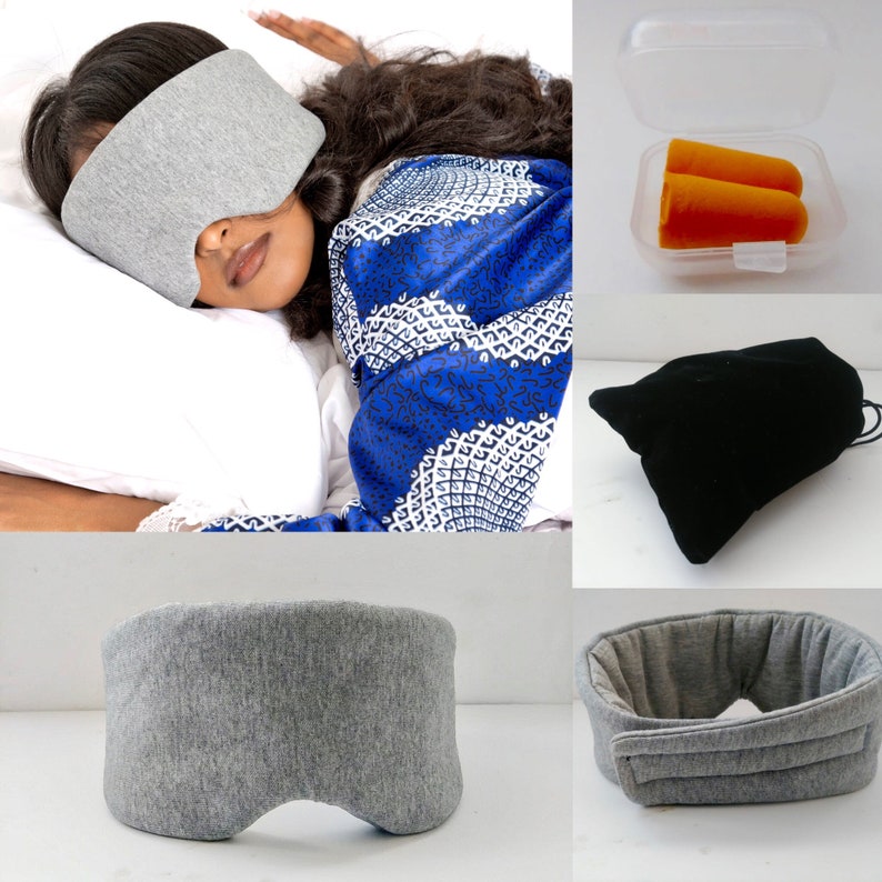 May include: A gray sleep mask with a contoured shape for comfortable eye coverage. The mask is made of a soft, breathable fabric. Also pictured are a pair of orange earplugs in a plastic container and a black velvet pouch.