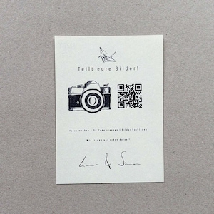 Könnte beinhalten: Eine weiße Karte mit einer Schwarzweißillustration einer Kamera und einem QR-Code. Der Text auf der Karte lautet "Teilt eure Bilder!"  "Fotos machen | QR Code scannen | Bilder hochladen"  "Wir freuen uns schon darauf!"  "L & S"