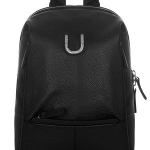 May include: A black backpack with a textured pebble-grain finish, featuring a silver-toned letter U emblem on the front, a top handle, adjustable shoulder straps, and a horizontal zippered pocket. The brand name MONTE DI JINNE is printed at the base.