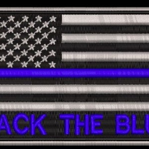 May include: An embroidered patch with a black and white American flag with a blue line across the middle. The text "BACK THE BLUE" is written in blue below the flag.
