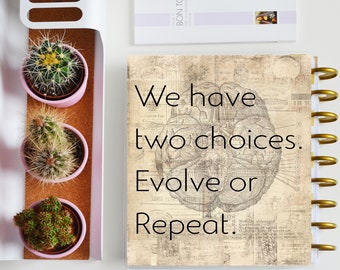 Può includere: Un quaderno in stile vintage con rilegatura a spirale dorata e una citazione motivazionale. La citazione dice "Abbiamo due scelte. Evolvere o ripetere."