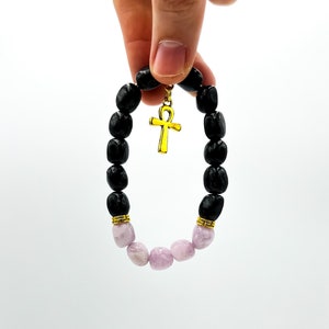 May include: Black and purple beaded bracelet with a gold ankh charm.