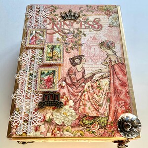 May include: A decorative box with a princess theme. The box features a pink floral design, the word "PRINCESS", and illustrations of women in dresses. Embellishments include lace, pearls, and a carriage charm.