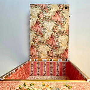 May include: A decorative box with a hinged lid, featuring a princess-themed design. The box is adorned with a floral pattern, images of princesses, and the text "Once Upon a Time". The interior has a pink and white striped pattern.