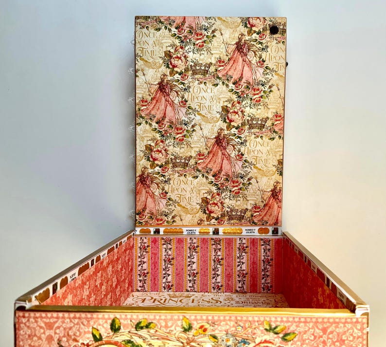 May include: A decorative box with a hinged lid, featuring a princess-themed design. The box is adorned with a floral pattern, images of princesses, and the text "Once Upon a Time". The interior has a pink and white striped pattern.
