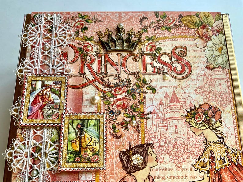 May include: A decorative scrapbook cover with a princess theme. The cover features the word "PRINCESS" in large letters, a crown, floral accents, and two postage stamp-style images. The color palette includes pink, red, and gold.