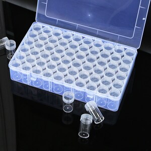 May include: A clear plastic storage box with a lid, containing many small clear plastic containers. The box is open and some of the containers are scattered around it.