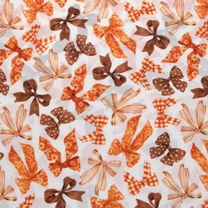 May include: A repeating pattern of bows on a white background. The bows feature various shades of orange, brown, and white, with designs including solid colors, polka dots, stripes, gingham checks, and floral prints arranged in a scattered layout.