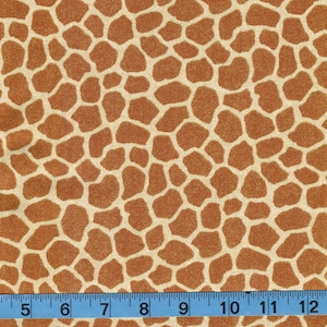 May include: A close-up of a brown and cream fabric with a giraffe print pattern. The fabric is textured and has a subtle sheen. A ruler is placed at the bottom of the image, showing measurements in inches.