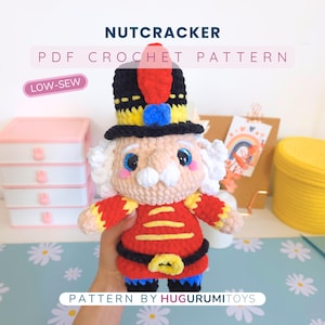 May include: A handmade crochet nutcracker doll with a red jacket, black belt, and a tall black hat with yellow and red accents. The doll has a white mustache and curly hair. The text "NUTCRACKER PDF CROCHET PATTERN" is displayed above the doll.