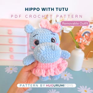 Könnte beinhalten: Ein handgefertigtes blaues Häkelpferd mit einem rosa Tutu und einer Schleife. Der Text "HIPPO WITH TUTU" und "PDF CROCHET PATTERN" sind über dem Nilpferd zu sehen. Der Text "Removable Outfit" ist ebenfalls sichtbar. Das Nilpferd ist ein Plüschtier.
