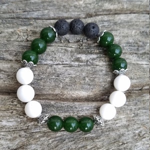 May include: A green and white beaded bracelet with silver accents. The bracelet has black lava beads and white beads with silver accents.