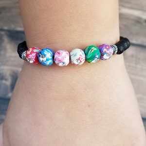 May include: A black lava rock bracelet with colorful floral patterned beads and silver accents.