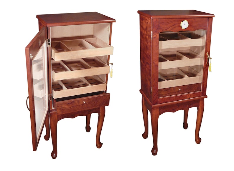 May include: A wooden humidor with a glass door and three shelves for storing cigars. The humidor has a drawer at the bottom and stands on four legs.