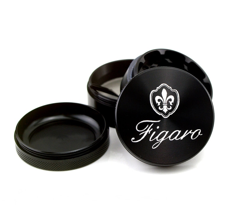 May include: Black metal grinder with a silver fleur-de-lis design and the word "Figaro" engraved on the top.