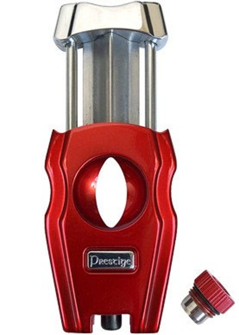 May include: A red and silver cigar cutter with a guillotine blade and a Prestige logo. The cutter has a built-in punch for smaller cigars.