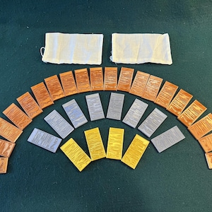 May include: A set of 20 wooden tiles in a rainbow of colors, including brown, gray, and gold. The tiles are arranged in a semi-circle shape, with the brown tiles on the outside and the gold tiles in the center.