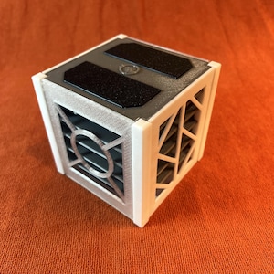 May include: A white cube with a black and gray patterned design on the top. The cube has a grid-like pattern on the sides.
