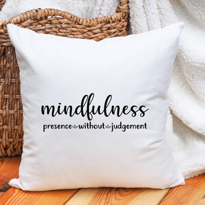 以下が含まれることがあります： 「mindfulness presence without judgement」と黒文字で書かれた白いクッションです。