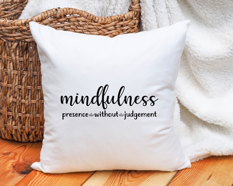 以下が含まれることがあります： 「mindfulness presence without judgement」と黒文字で書かれた白いクッションです。