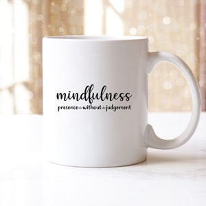 以下が含まれることがあります： 「mindfulness presence without judgement」という黒い文字が書かれた白いセラミックマグカップです。