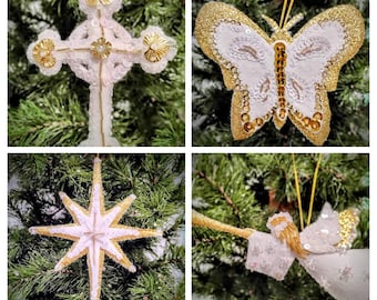 Könnte beinhalten: Eine Sammlung von vier Weihnachtsschmuckstücken. Die Ornamente umfassen ein weißes Kreuz mit goldenen Akzenten, einen Schmetterling mit goldenem Glitzer und weißen Pailletten, einen Stern mit goldenem Glitzer und weißen Akzenten und einen weißen Engel mit goldenen Akzenten.