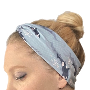 May include: A light blue headband with a pattern of orcas and fish swimming in the ocean. The headband is made of a soft, stretchy fabric and is perfect for keeping hair out of your face.