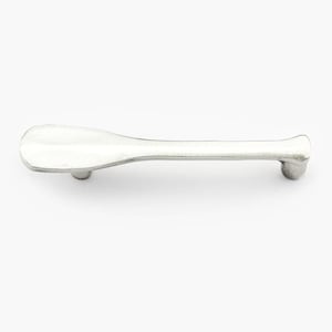 May include: A silver cabinet pull with a paddle-shaped handle and two small, round mounting posts. The handle is approximately 12.7 cm long, with a slightly textured surface. The hardware is designed for use on drawers or cabinet doors.