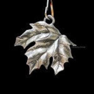 May include: A silver maple leaf pendant charm with a detailed design. The pendant is ready to be added to a necklace or bracelet.