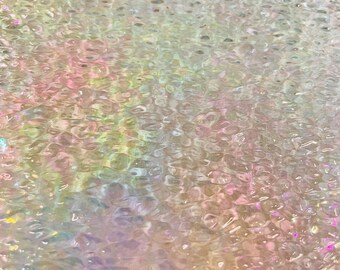 May include: Abstract, iridescent surface with a textured, bubbly pattern. The colors shift from pale yellow and green to soft pink and purple, creating a shimmering, ethereal effect. The overall appearance is reminiscent of water or a soap bubble.