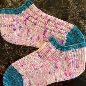 May include: A pair of pink and teal ankle socks with a speckled pattern. The socks are made of a soft, knitted fabric.