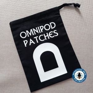May include: Black drawstring bag with white text that reads "Omnipod Patches" and a white outline of a large letter D. A blue and yellow bee logo with the text "Majestic Bee Tid Crafts" is in the lower right corner.