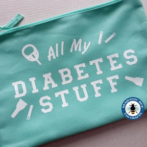 May include: A turquoise zippered pouch with the text "All My Diabetes Stuff" in white. The pouch also features a small white image of a blood glucose meter and a lancet.